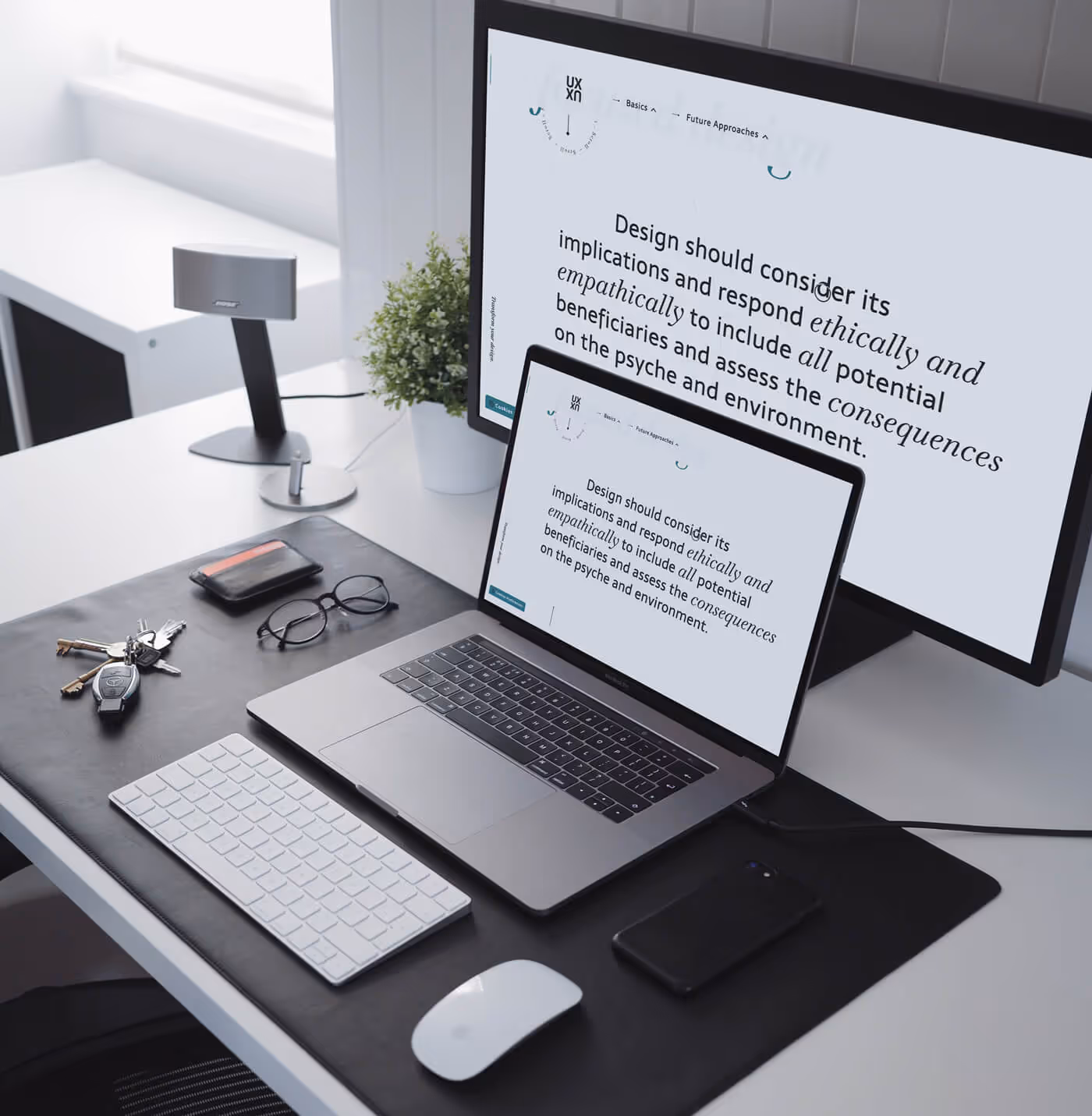 Laptop und Desktop-PC auf einem aufgeräumten Schreibtisch in einem Büro zeigen responsive Version der. Website „Future of UX“. Einer Auseinandersetzung mit der Zukunft des UX-Design, deren Wissen im Rahmen von Illunade angewandt wird.